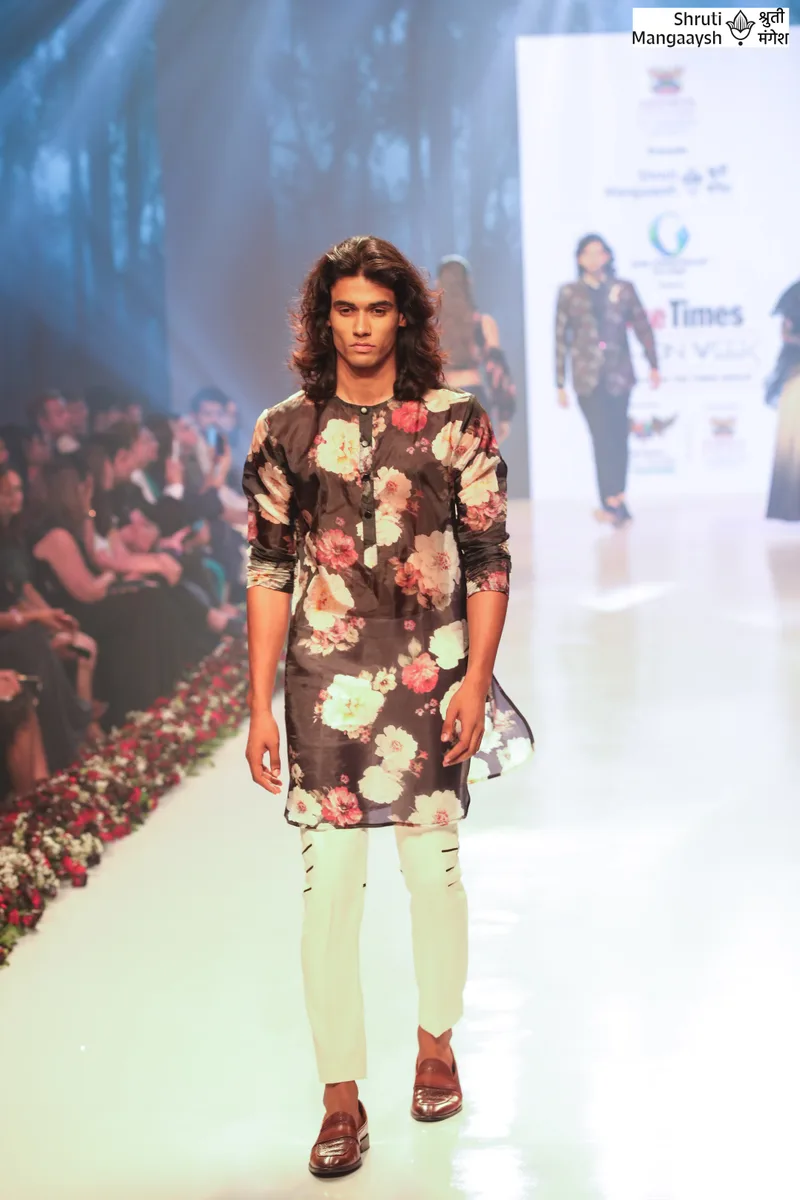 Model wearing a dark floral jacket with pale green trousers