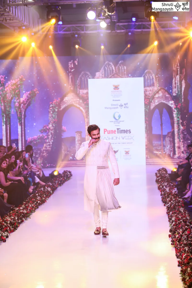Ivory outfit on the runway beneath yellow stage lights