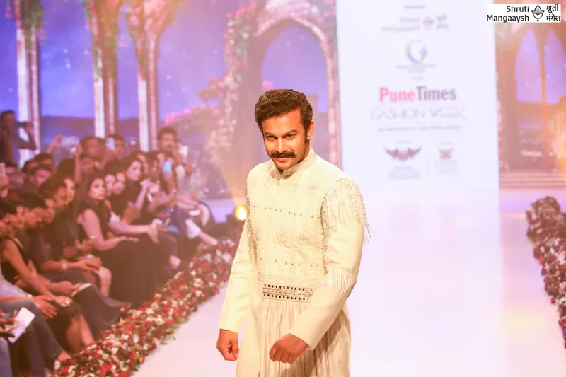 Model in an ivory outfit beside the seated runway audience