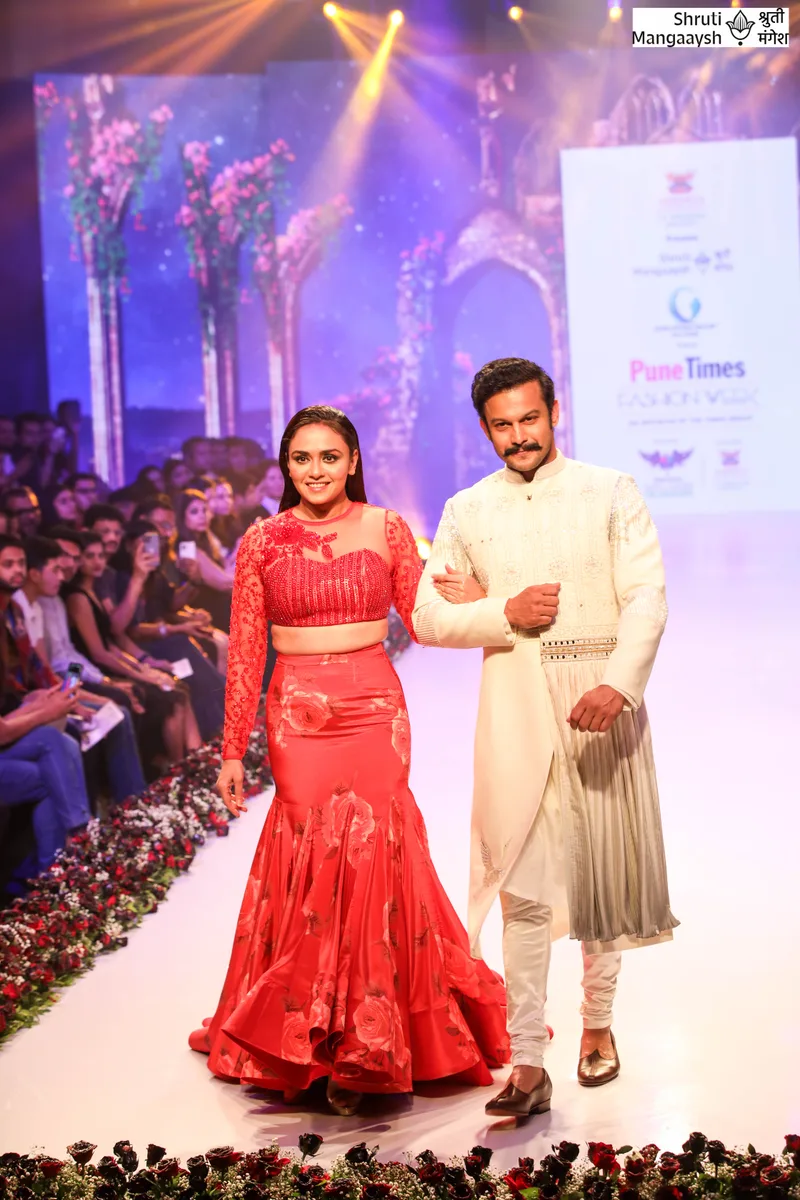 Two models wearing red and ivory outfits on the runway