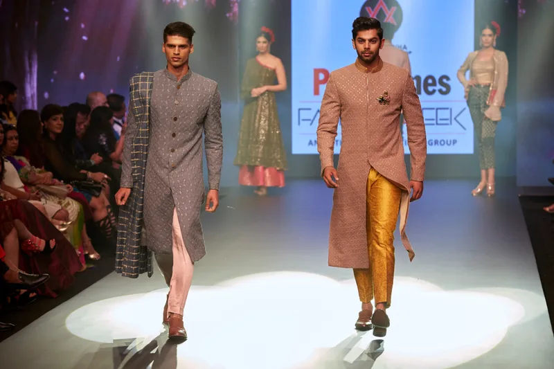 Two models walking in grey and rust-coloured kurtas