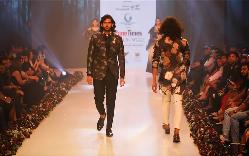 Two models wearing dark floral jackets on the runway