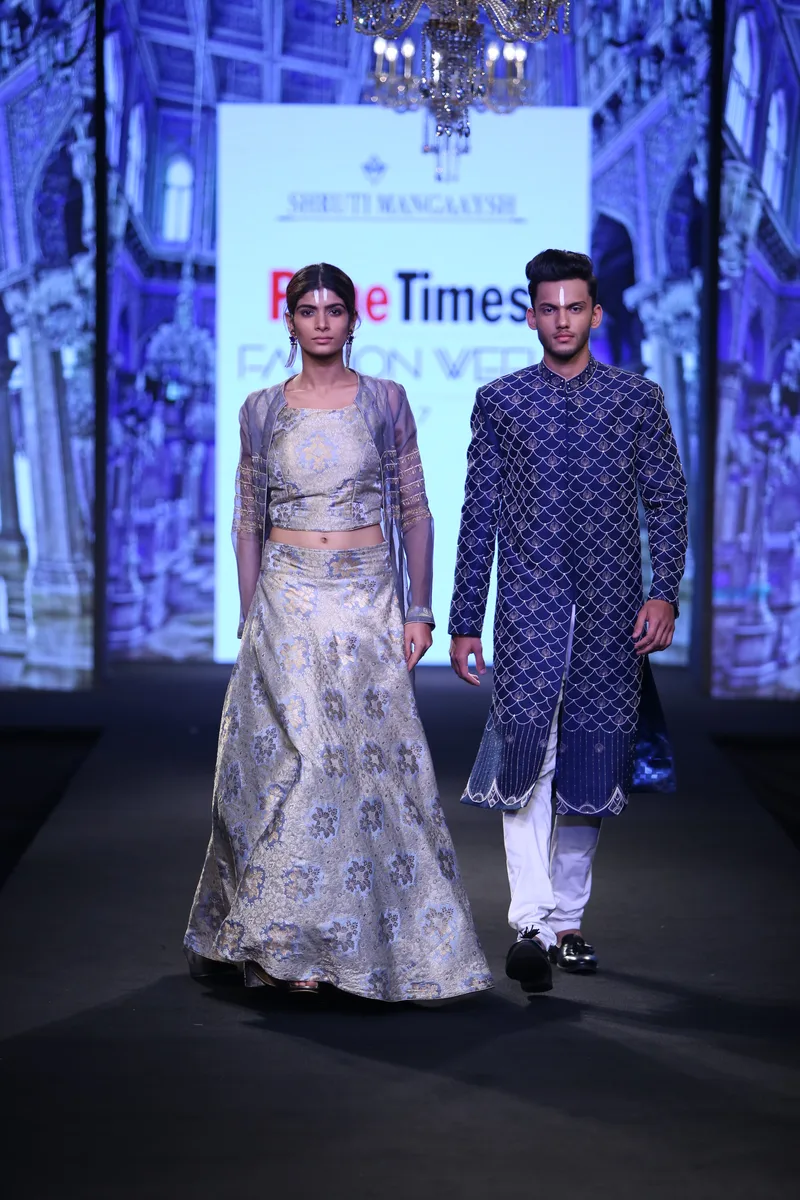 Two models wearing a silver gown and a blue patterned sherwani