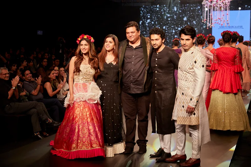 Group posing on the runway in red, ivory and black outfits
