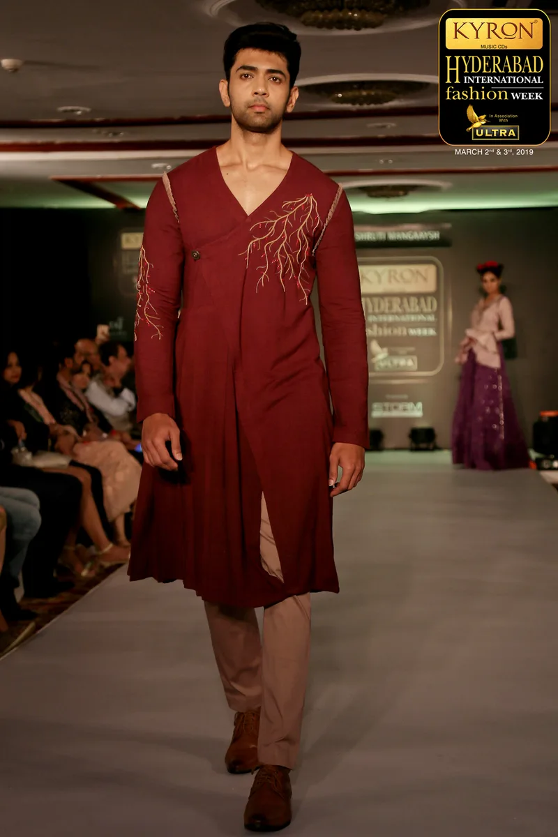 Model wearing a burgundy embroidered kurta on an indoor runway