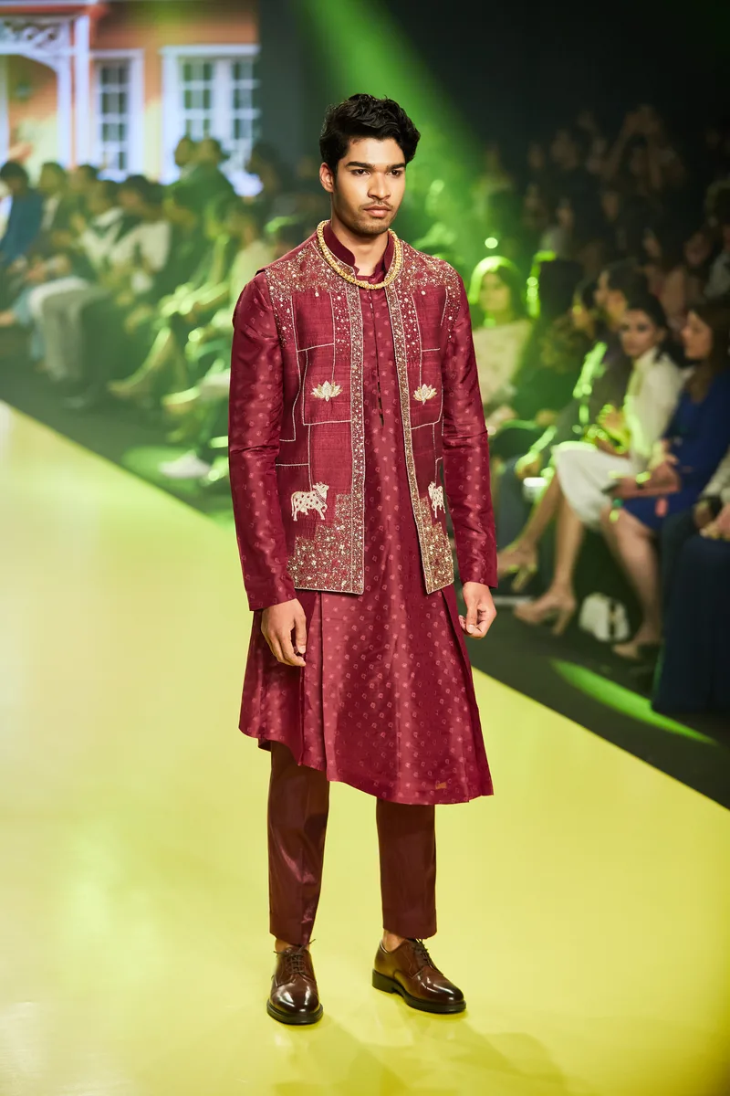 Model wearing a burgundy sherwani with embroidered details