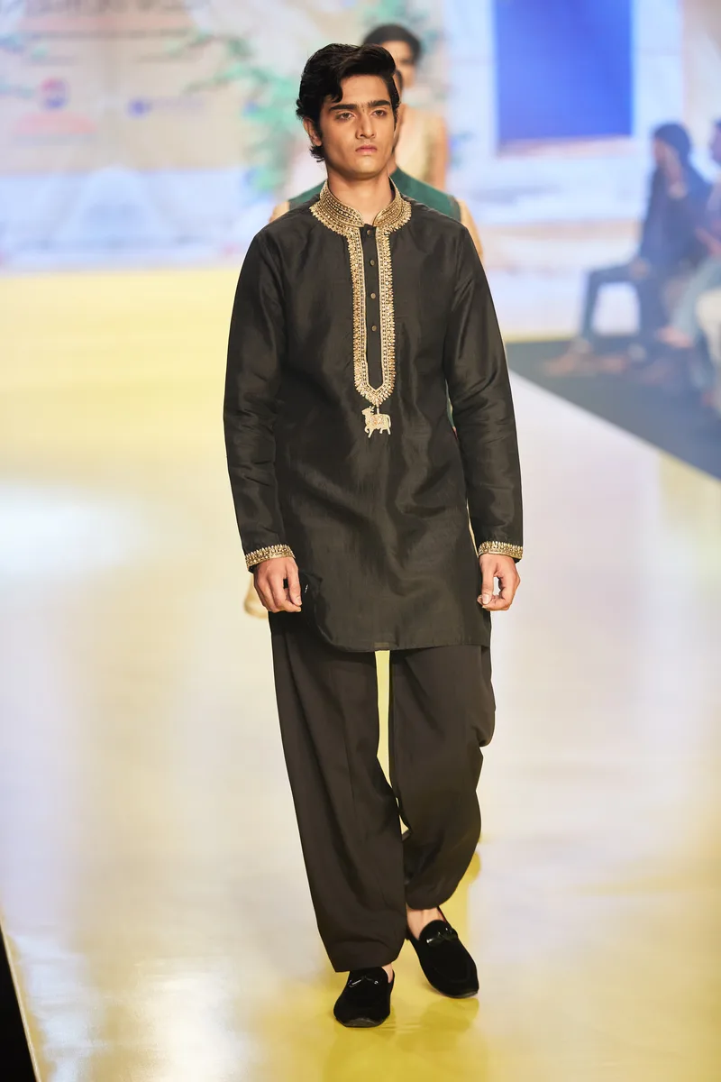 Model wearing a black kurta with gold embroidery