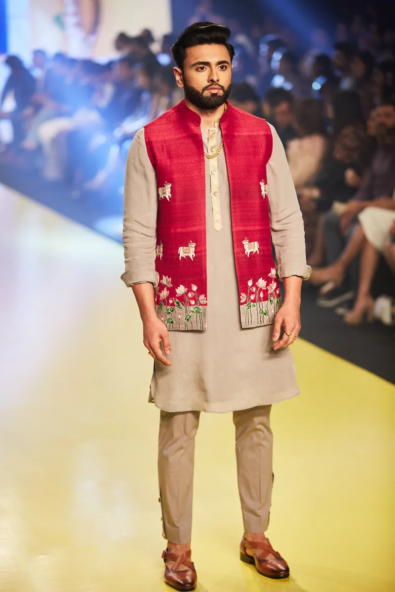 Model wearing a red waistcoat over a beige kurta set