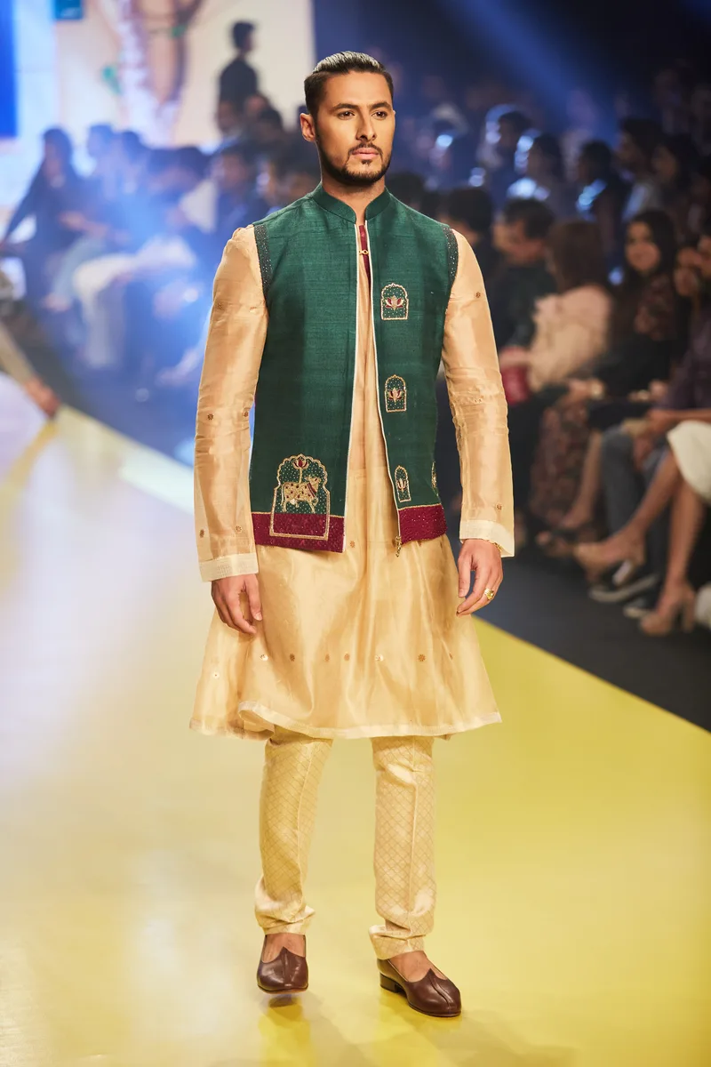Model wearing a green embroidered waistcoat over a gold kurta set