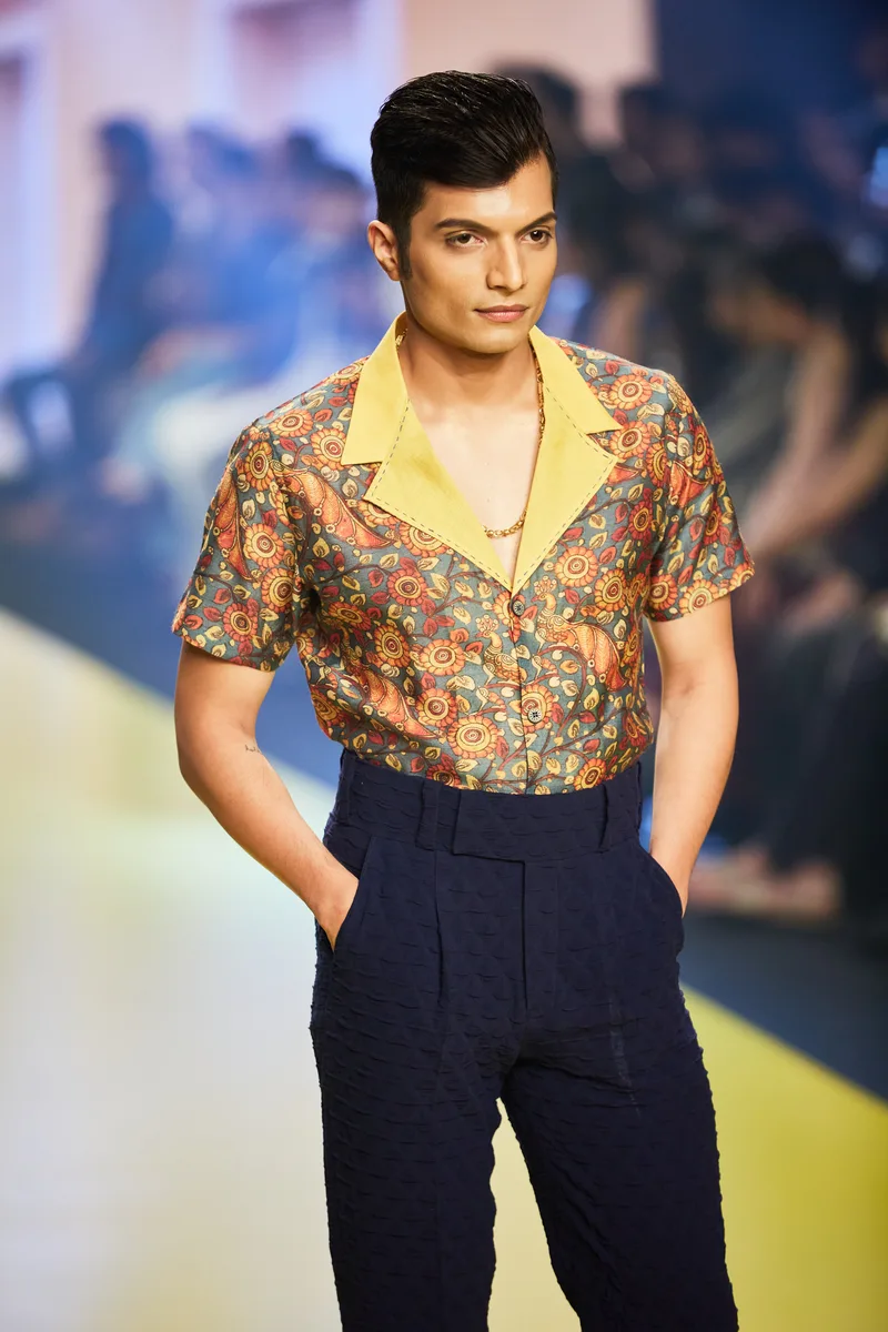 Model wearing a multicoloured printed shirt and dark blue trousers
