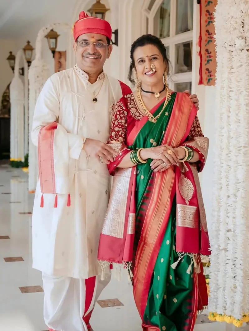Couple wearing an ivory kurta with red turban and a green and red sari